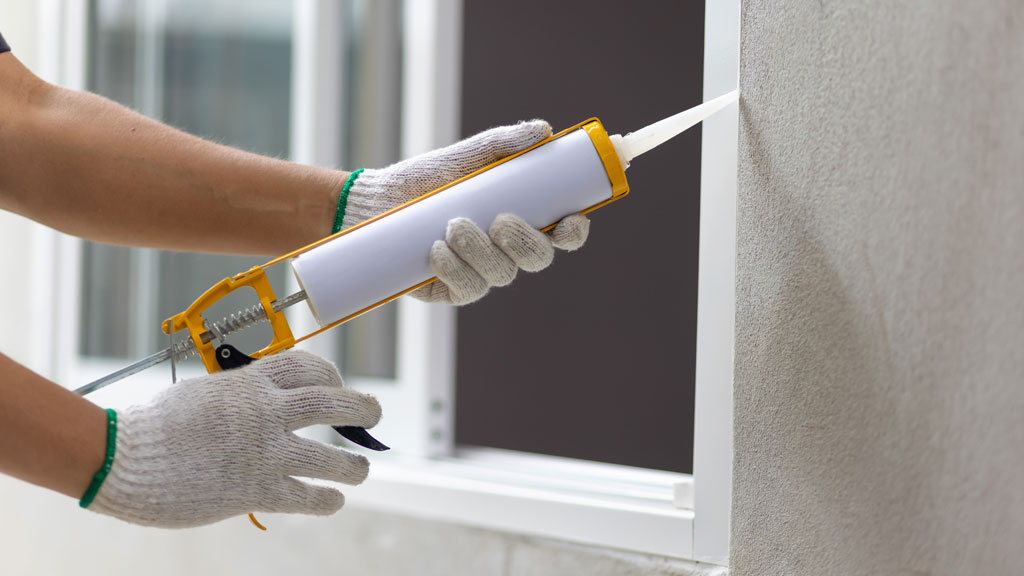 Technicien calfeutrage appliquant scellant sur cadre fenêtre extérieur