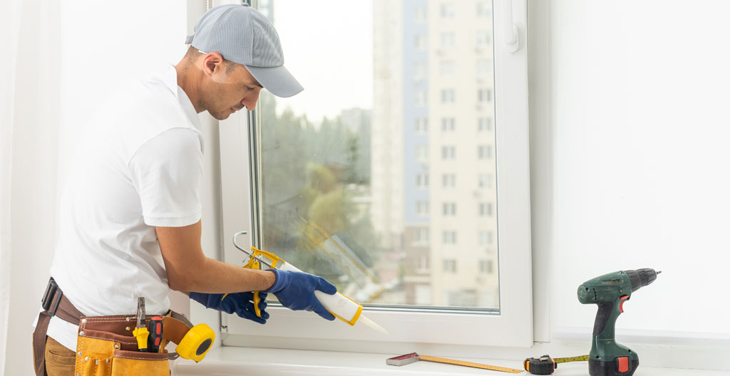 Technicien inspectant le calfeutrage extérieur autour du cadre d'une porte d'entrée au Québec